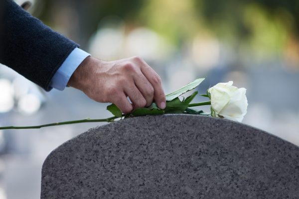 Paying his respects… Cropped shot of a man placing a white rose on a grave